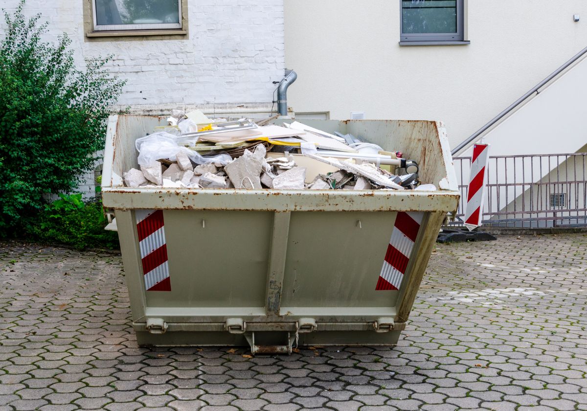 Großer Abrollcontainer wird per LKW auf eine Baustelle geliefert – visualisiert den flexiblen Containerdienst von RWR Recycling für Bauschutt, Schrott und Gewerbeabfälle.