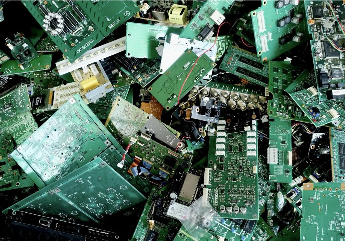 Elektroschrott, wie ausgediente Computer, Kabel und Platinen, liegt sortiert auf einer Recyclingfläche – zeigt die fachgerechte Entsorgung von Gewerbe-Elektroschrott durch RWR Recycling.